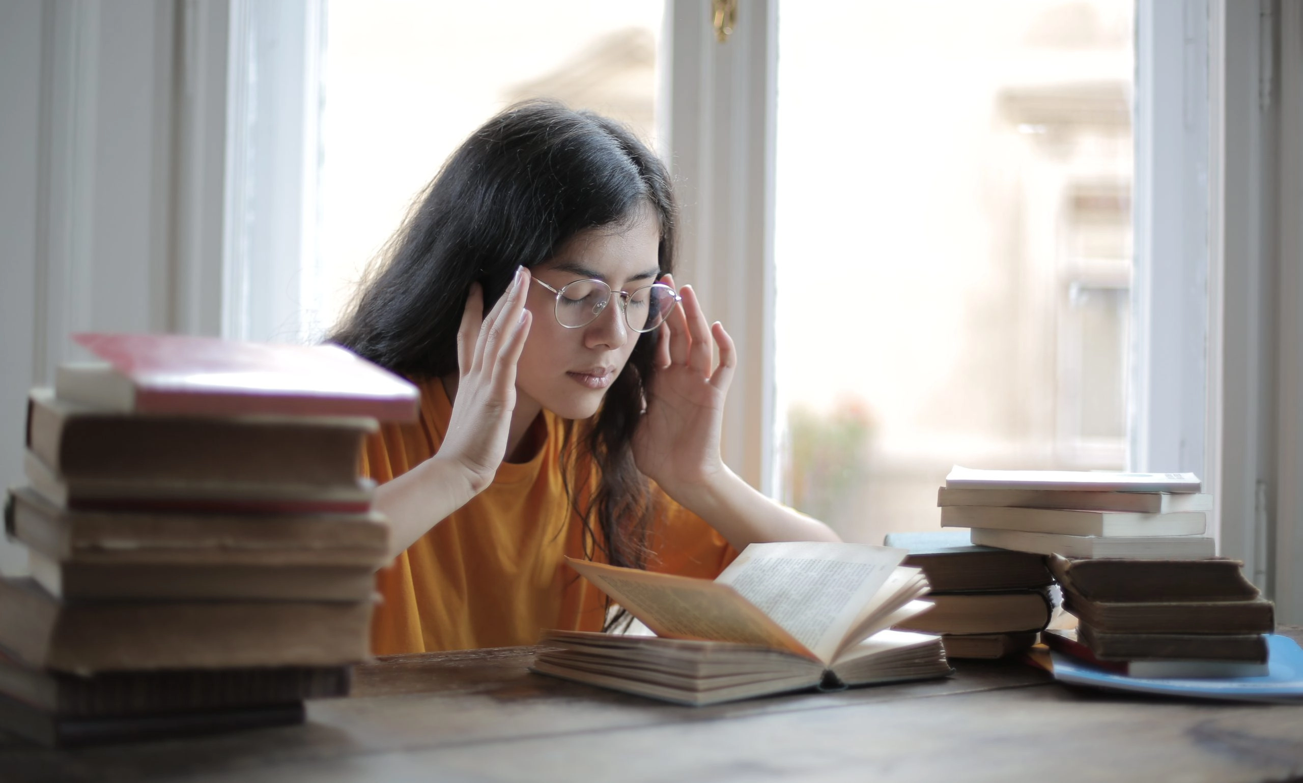 girl struggling with a migraine with her hands on her head