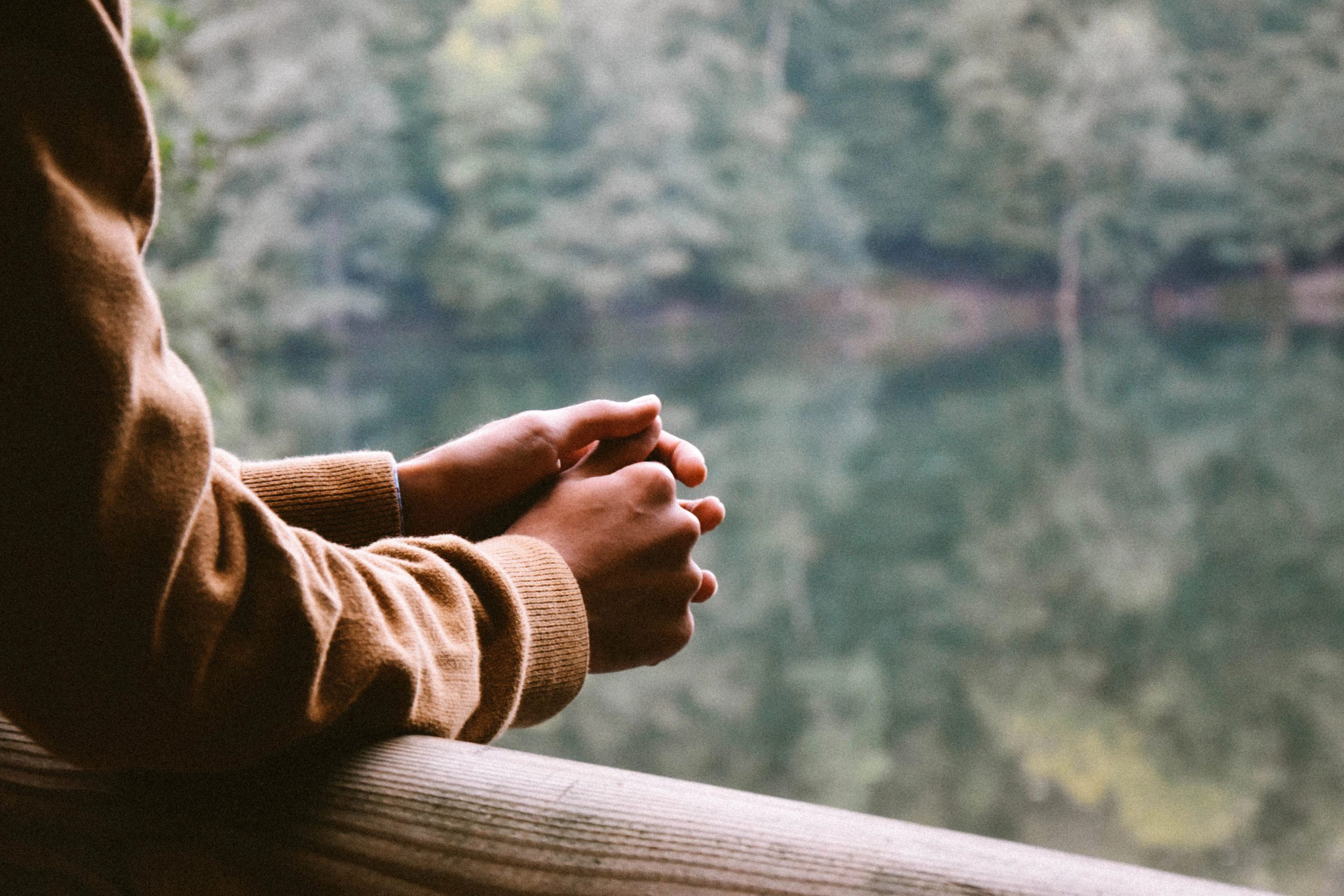 up close shot of person's hands resting on a balcony