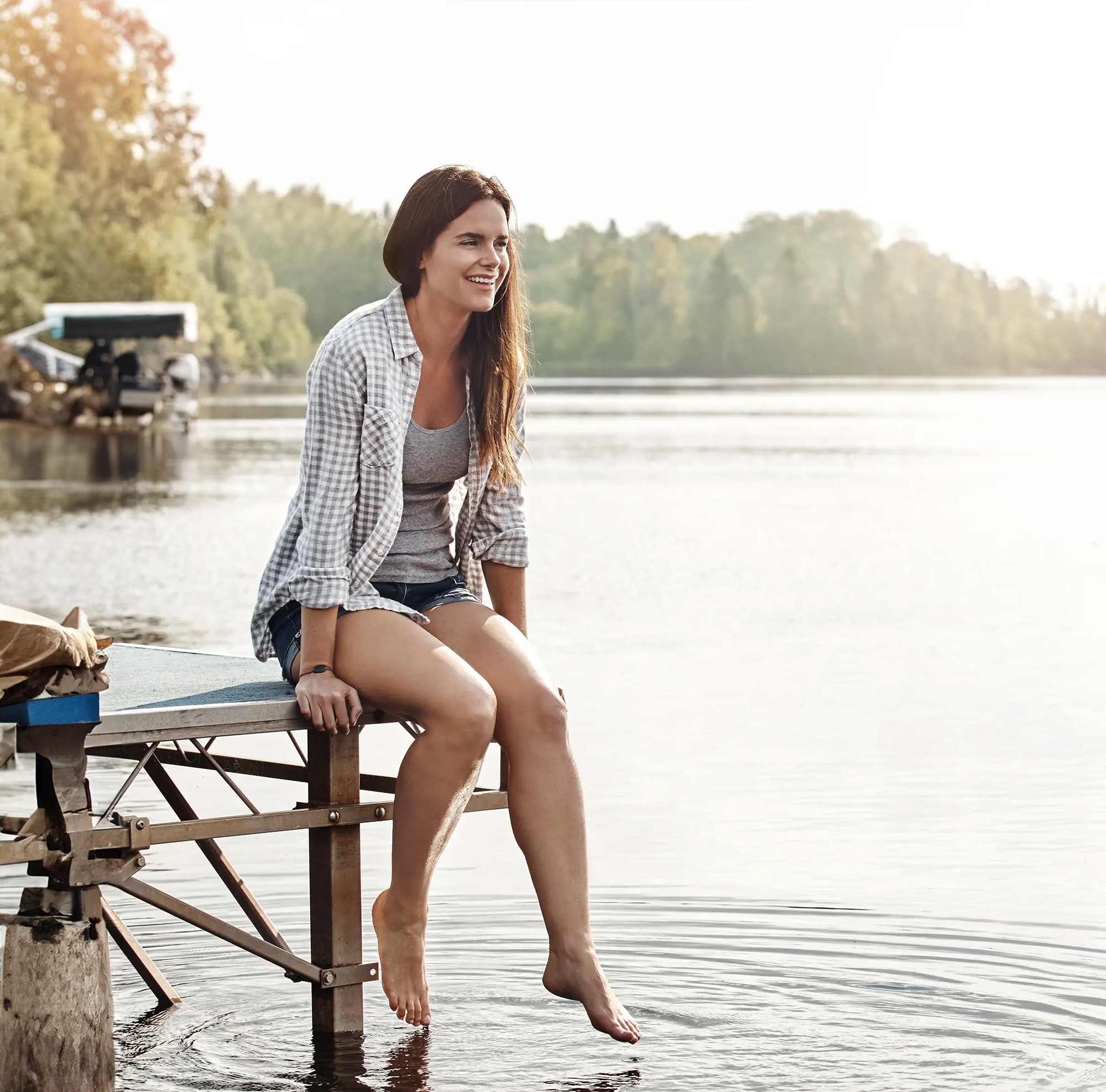 girl sitting on the dock with her feet touching the water and smiling