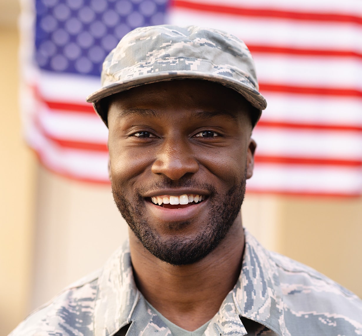 Smiling military veteran in uniform standing in front of American flag