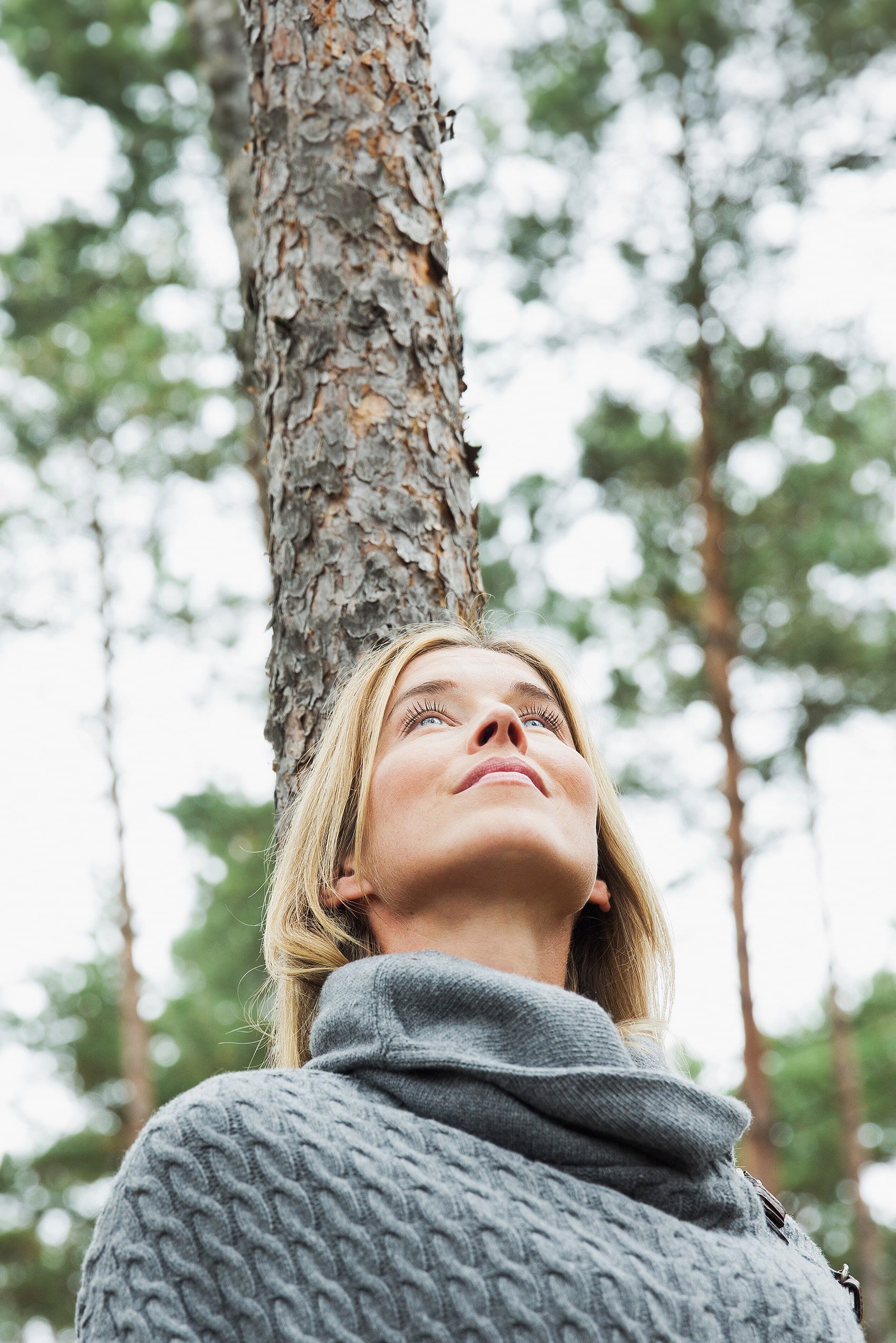 woman walking in the woods with a tree behind her